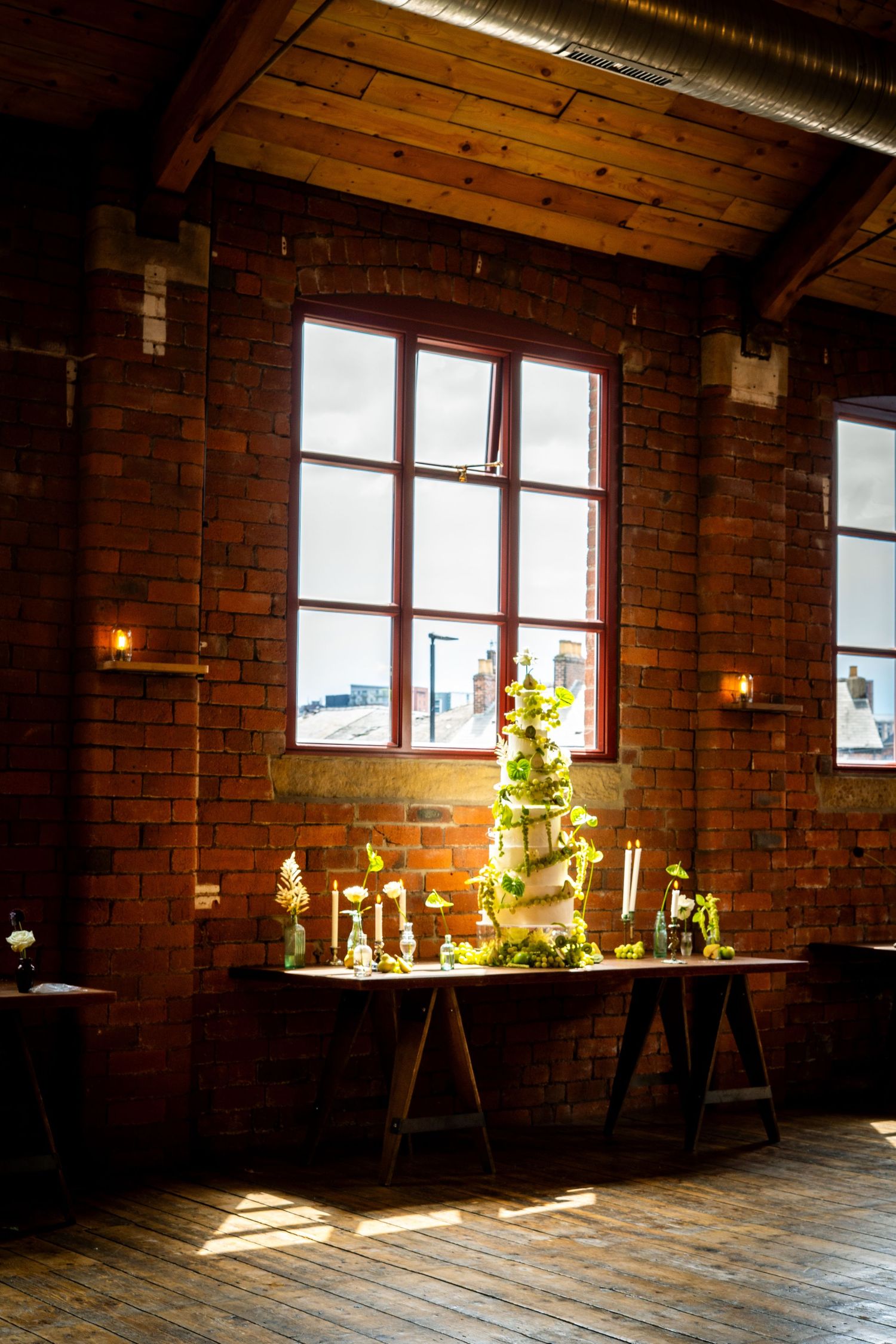 Wide angle view of wedding cake display in industrial venue with dramatic natural lighting.