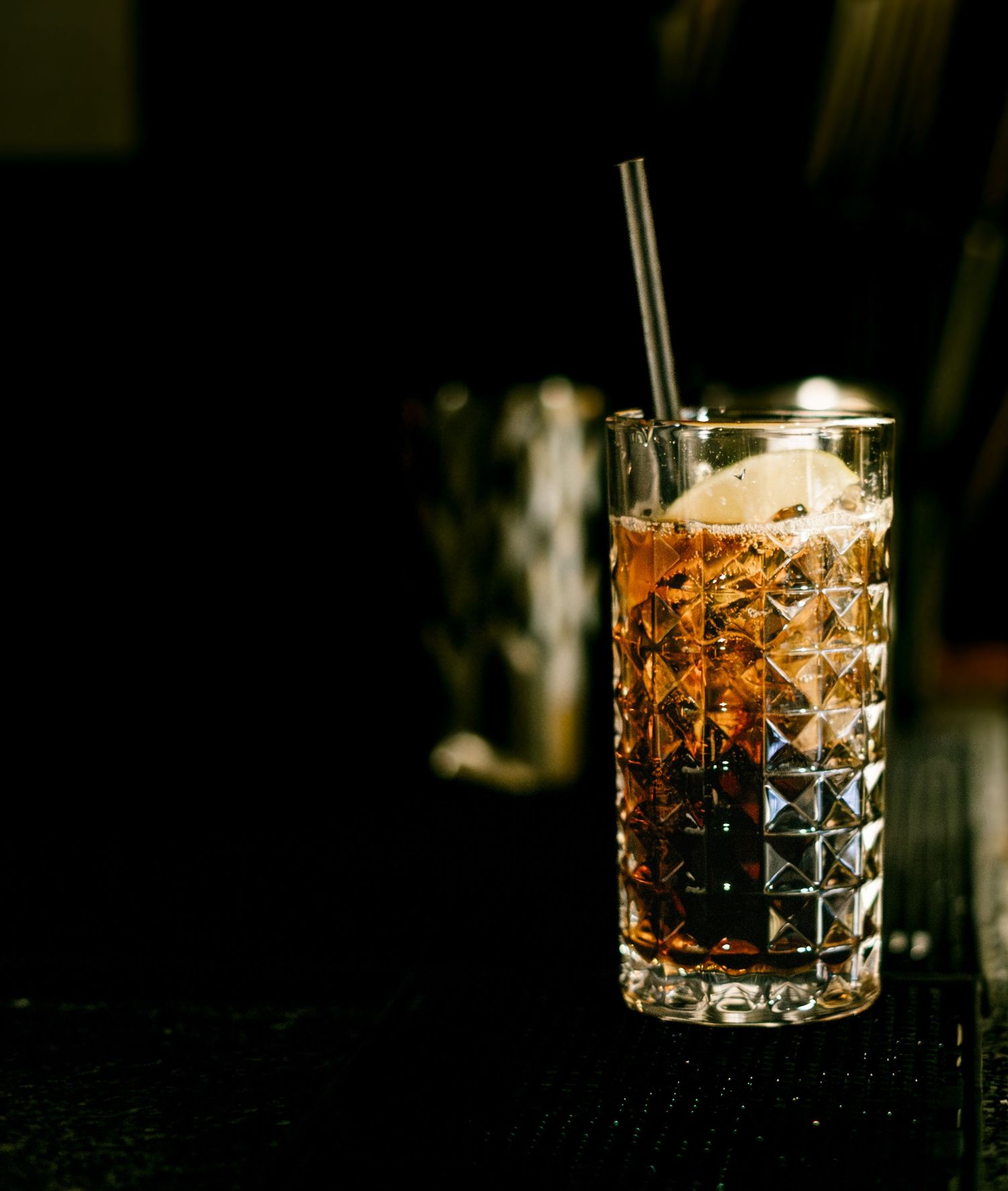 Amber-colored cocktail in a crystal cut rocks glass with dramatic lighting.