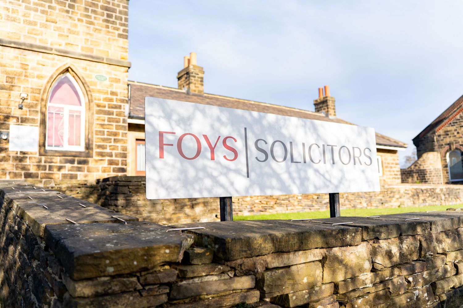 Stone wall exterior of a law office building with Foys Solicitors signage.