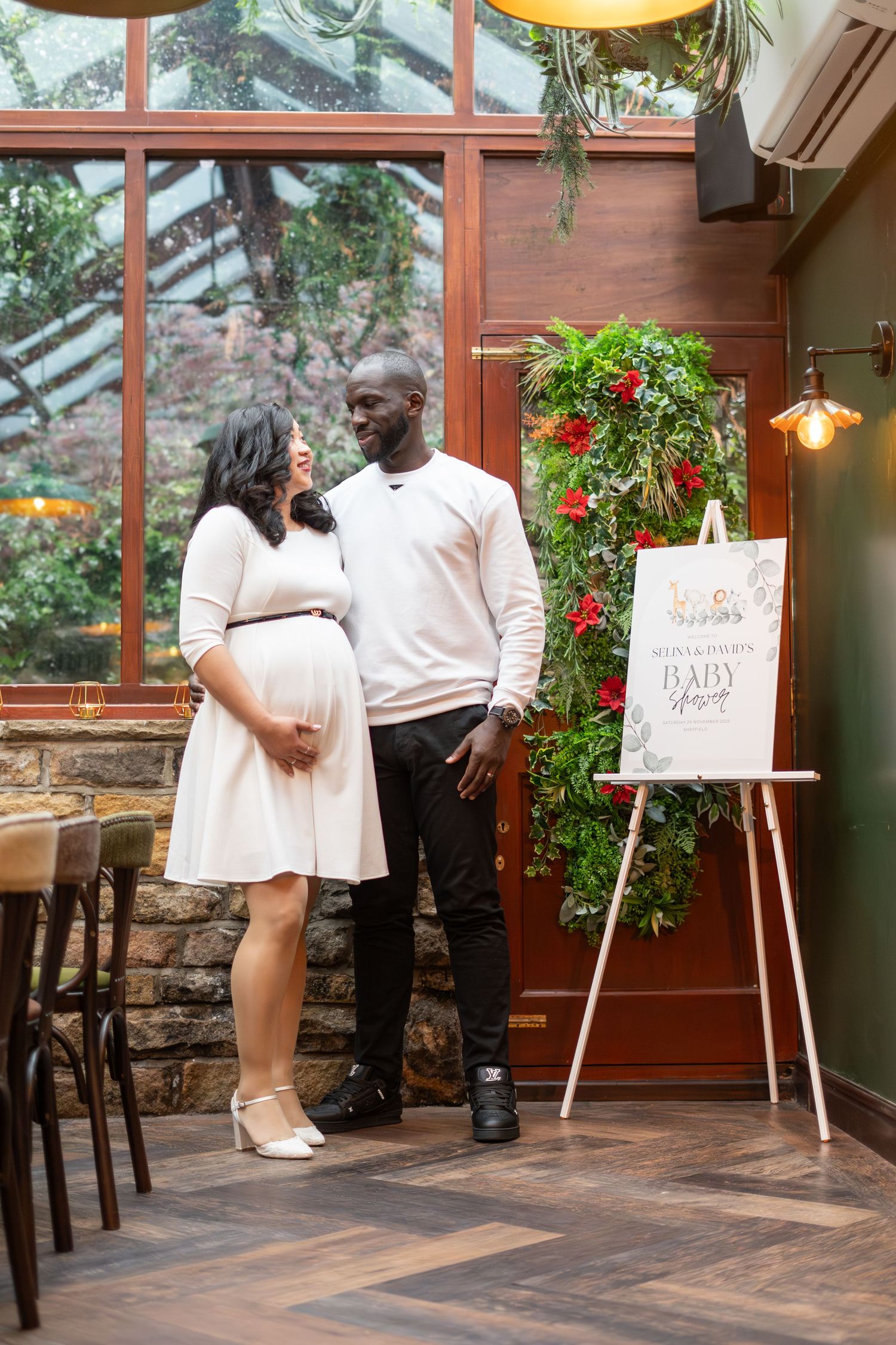 Intimate baby shower gathering in a glass-enclosed venue with rustic decor.