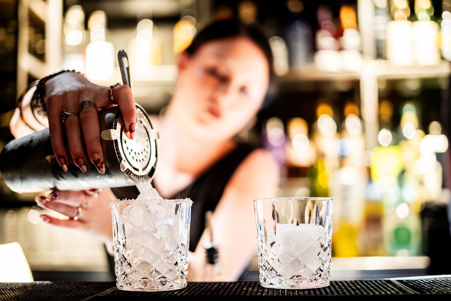Crystal glassware being prepared for cocktail service at an upscale bar.
