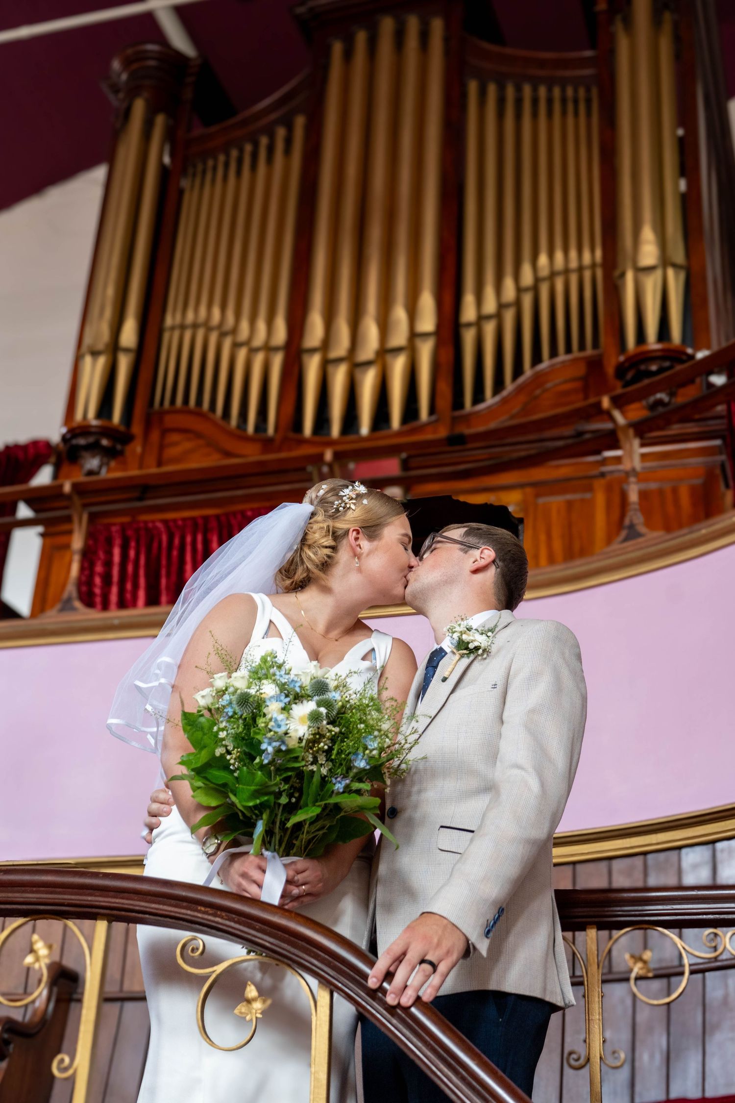 Wedding couple posing in front of church organ pipes in romantic sequence.
