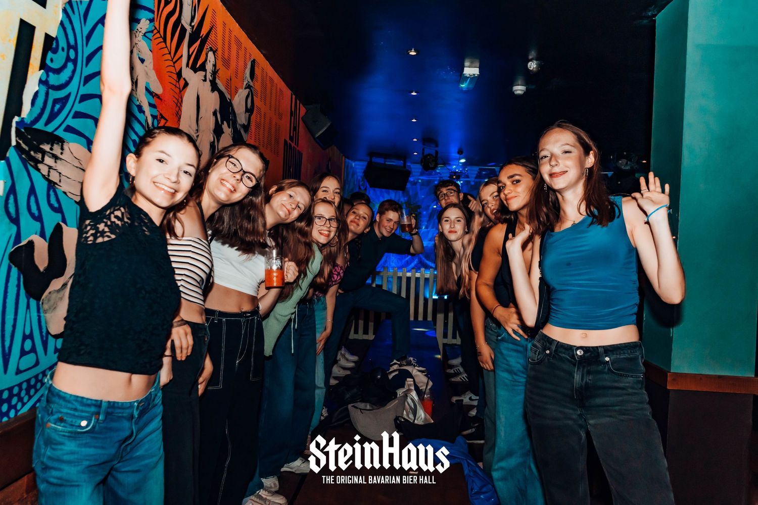 Crowded dance floor scene with blue and orange lighting at Steinhaus venue.
