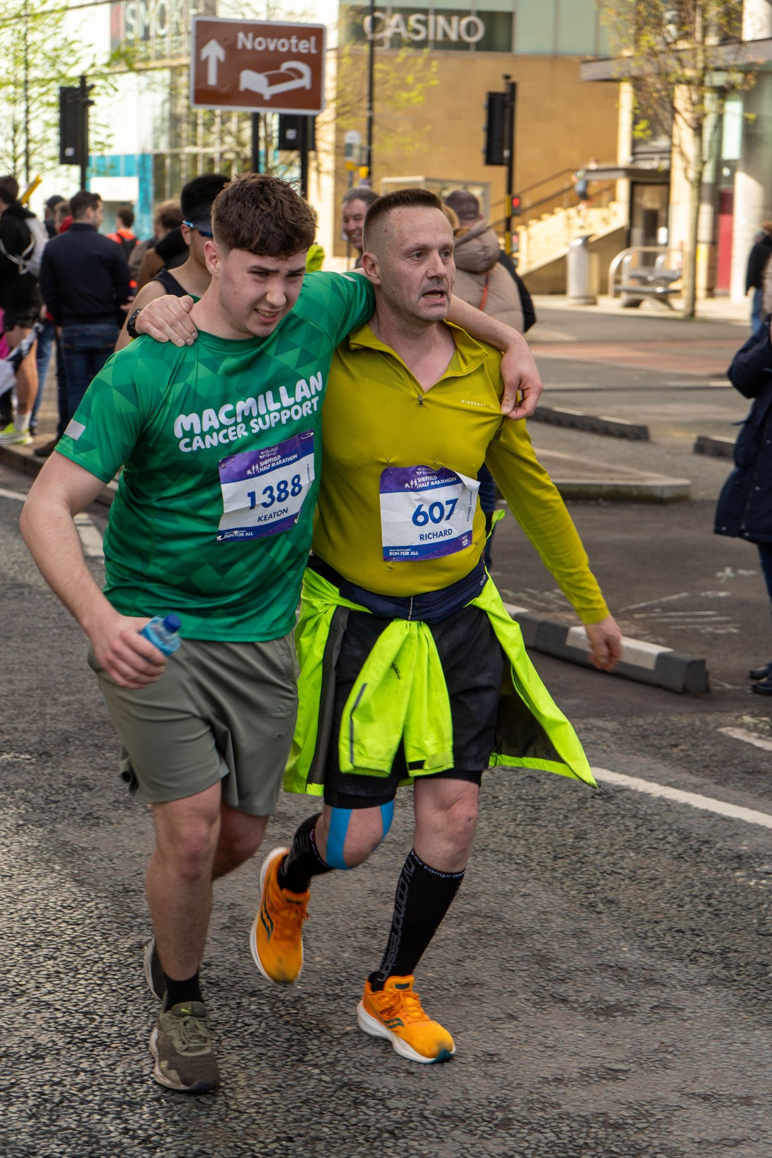 Two runners in bright athletic wear support each other during charity marathon.