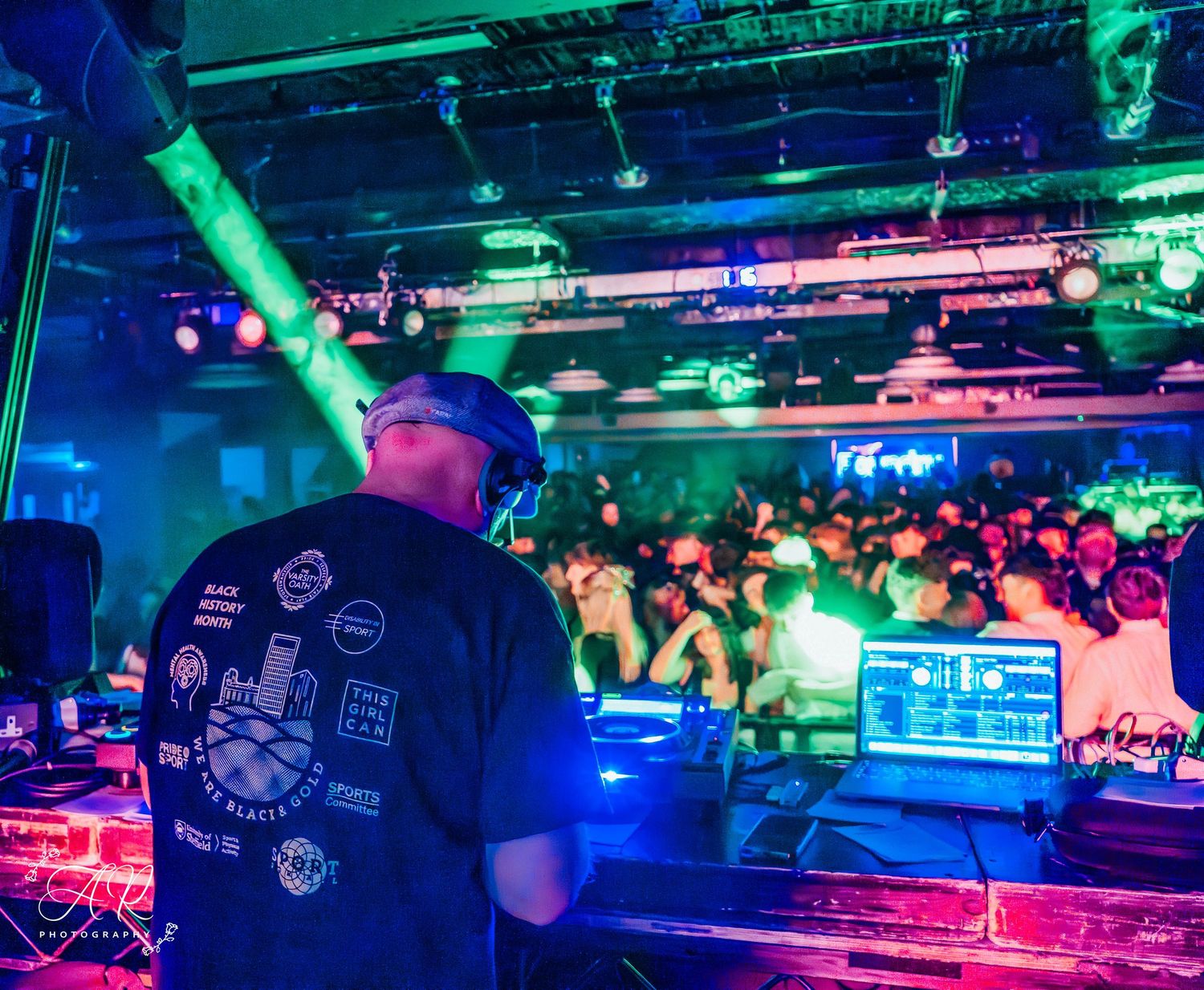 DJ working the decks at a packed nightclub with blue and red lighting effects.