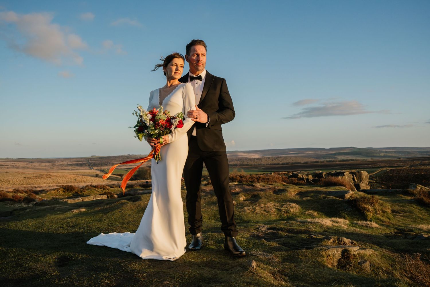 Dramatic landscape wedding photos taken at sunset on rocky cliffs.