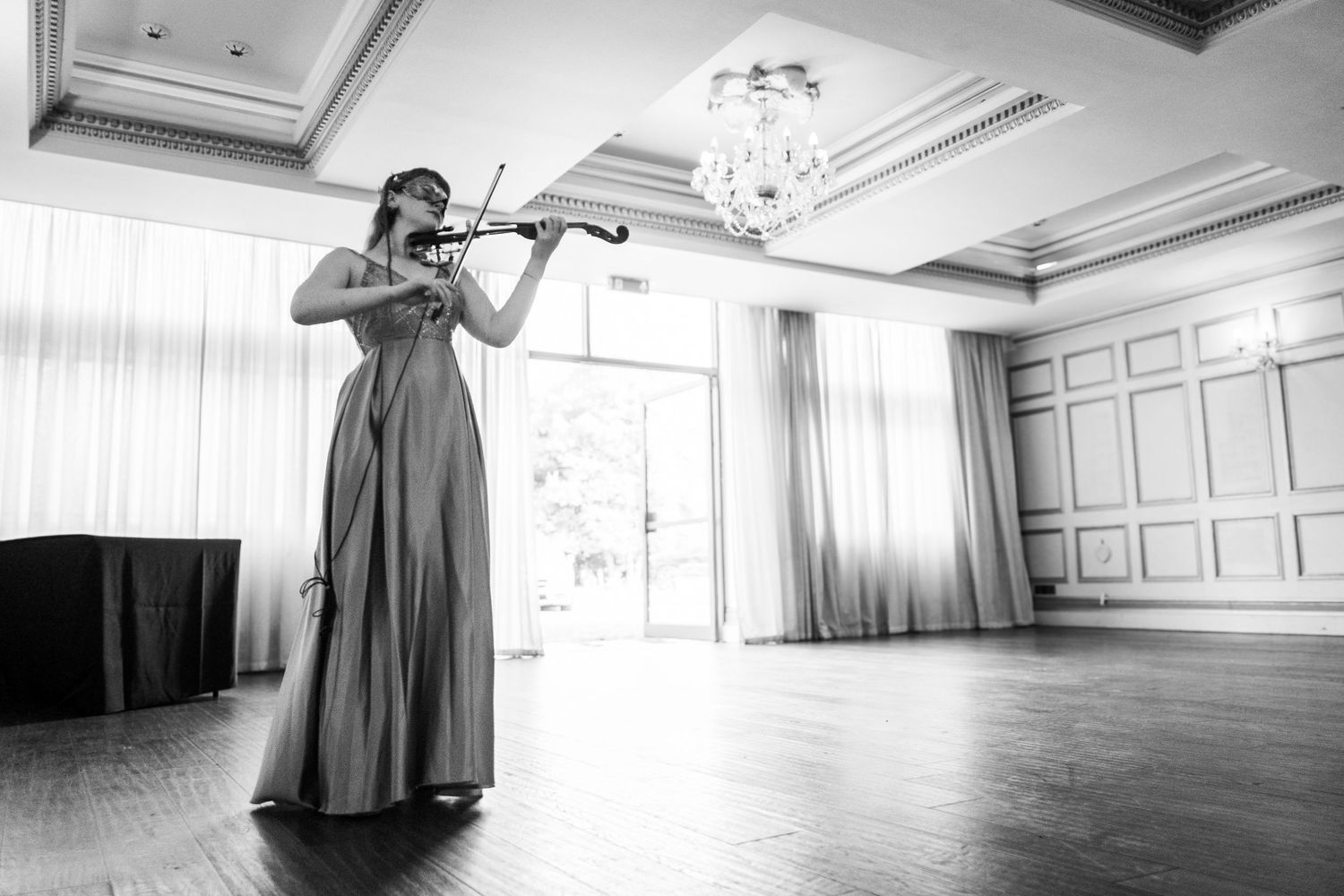 Black and white photo of musicians performing in a bright, minimalist room with paneled walls.