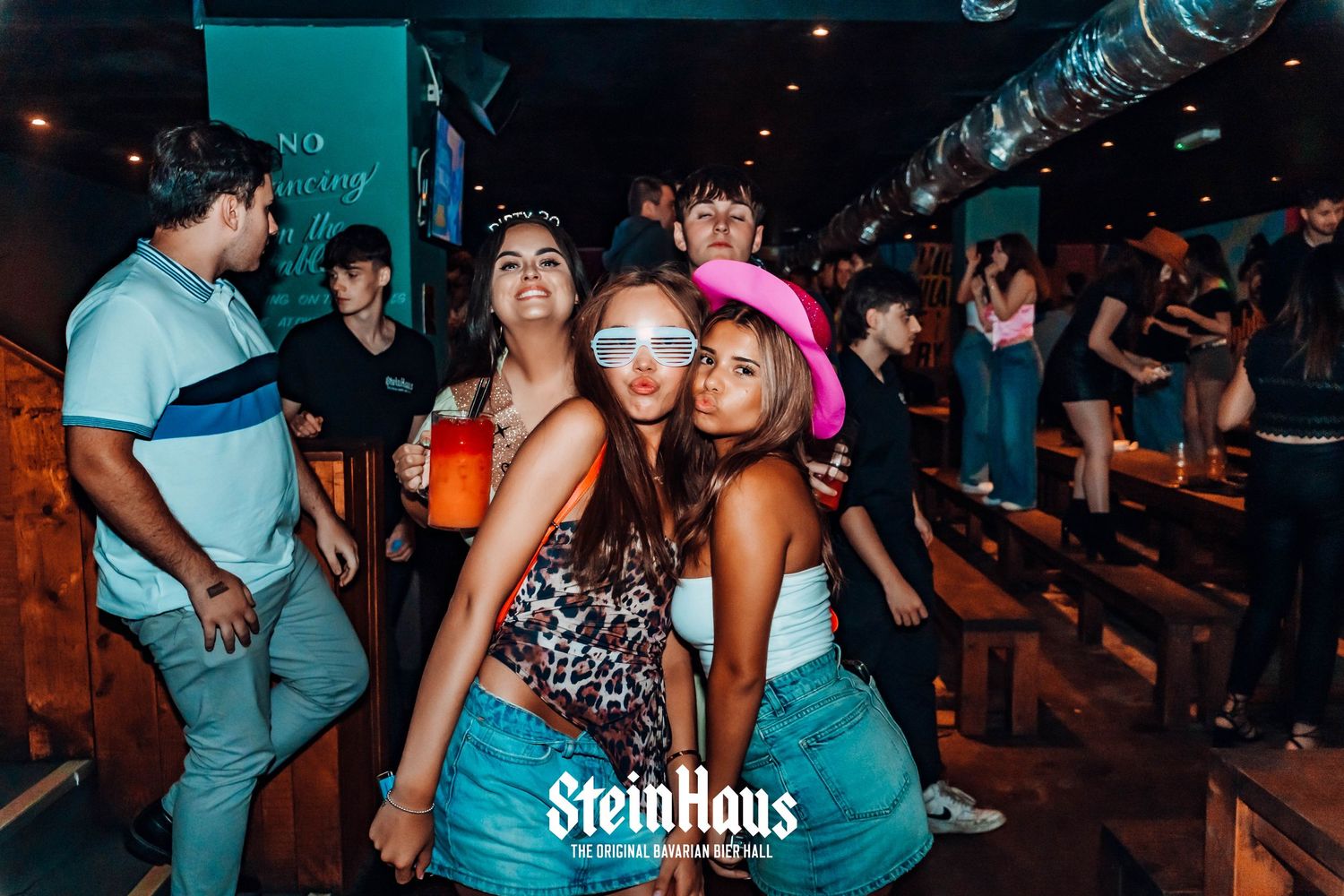 Group of friends celebrating with drinks at a lively nightclub event.
