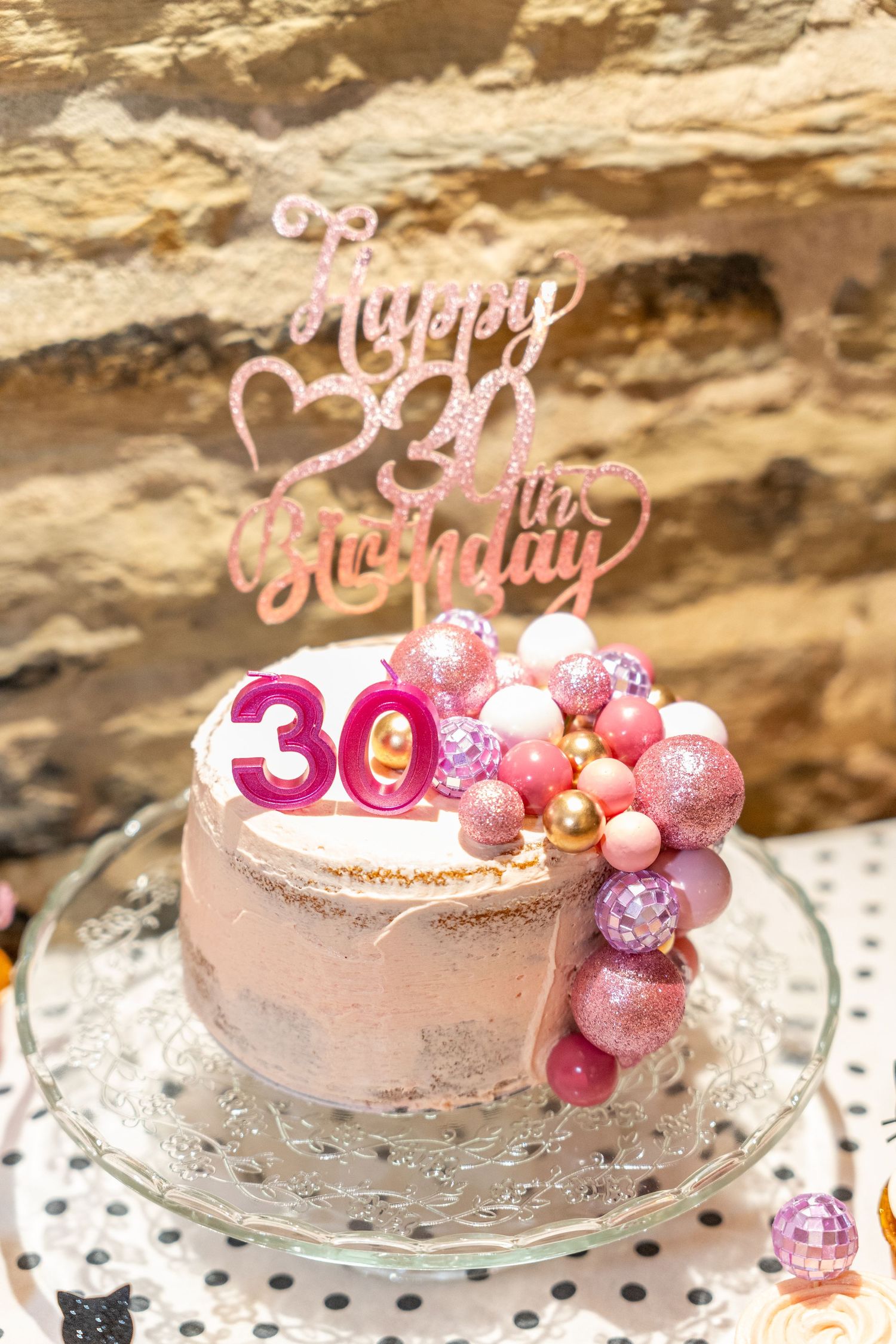 Pink and rose gold birthday cake decorated with '30' topper and metallic baubles.