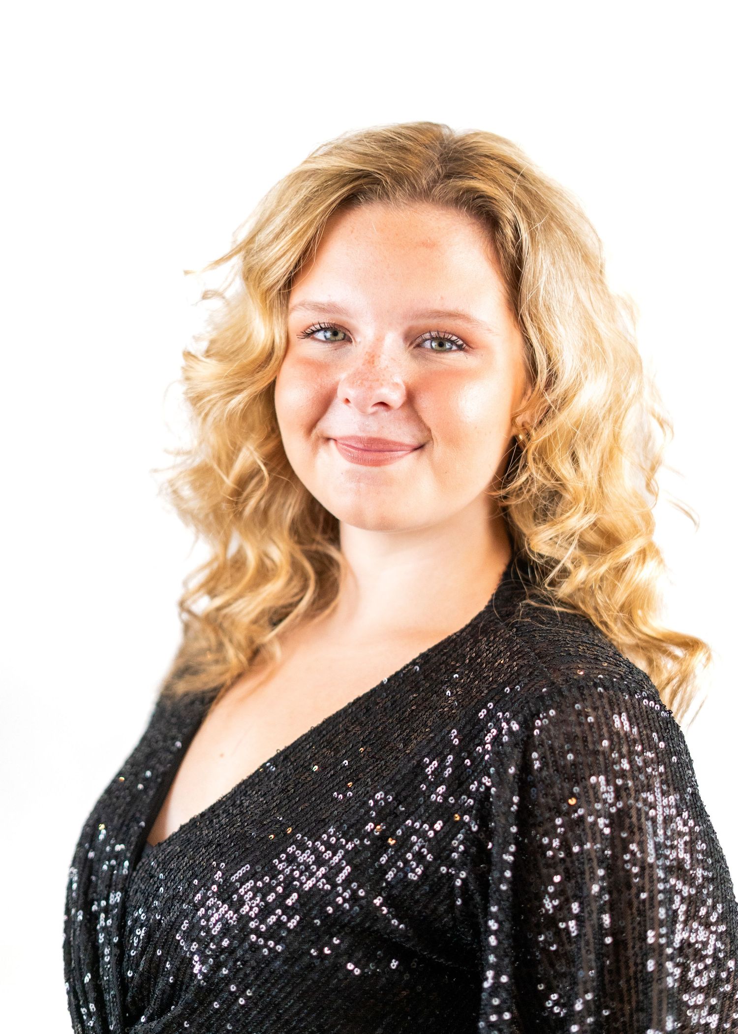 Performer in a sequined black dress poses expressively with a microphone.