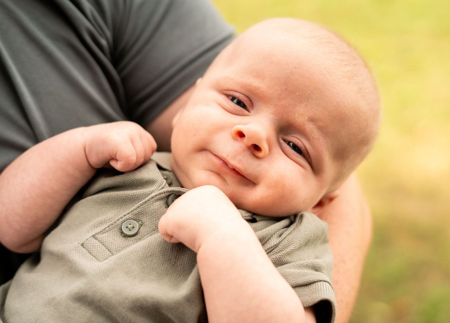 Sweet baby smiling while wearing a grey outfit.