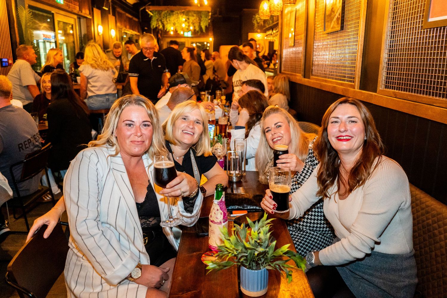 Lively crowd enjoying drinks and conversation at a warmly lit bar venue.