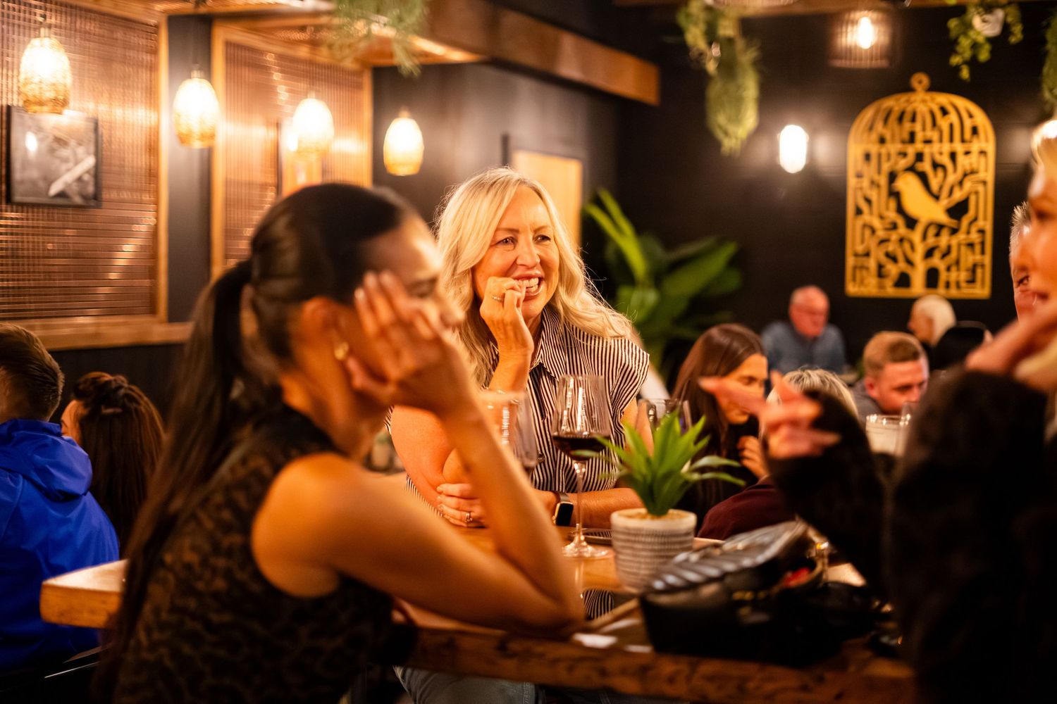 Interior view of a dimly lit restaurant with hanging lights and natural decor elements.