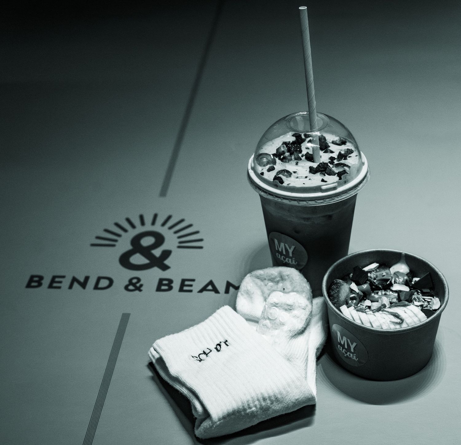 Branded merchandise and drinks displayed with Bend & Bean logo in moody lighting.
