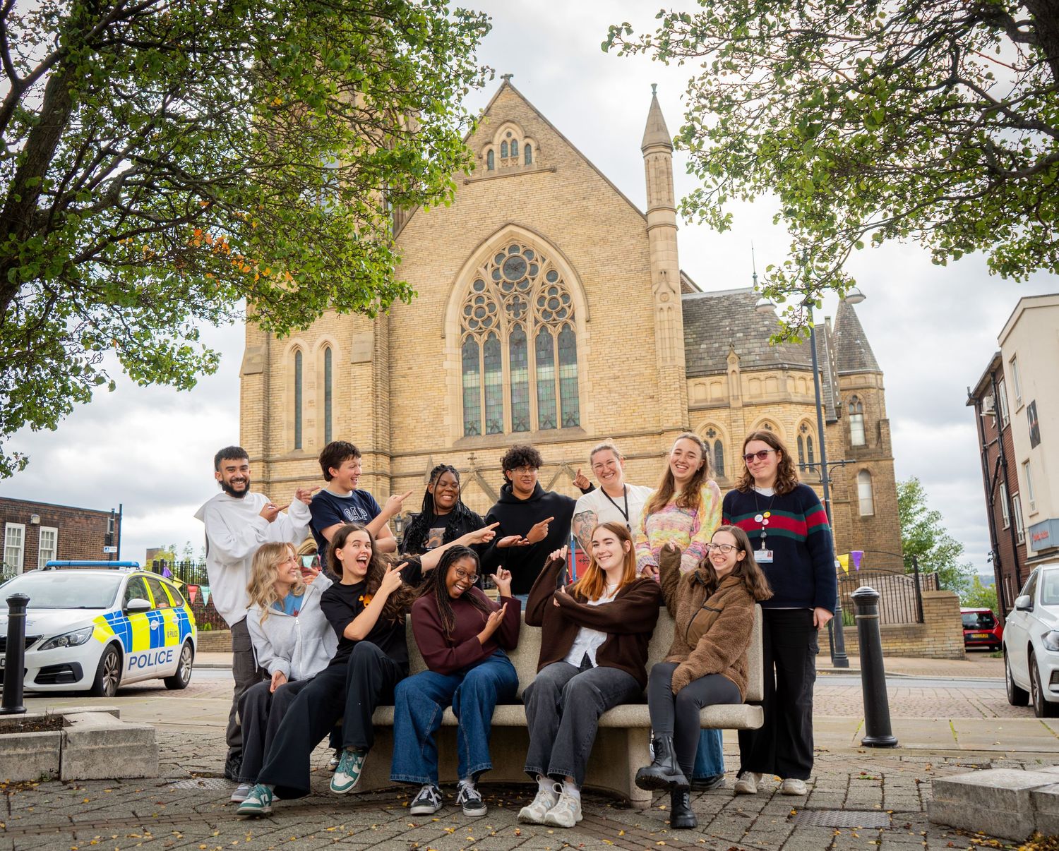 Group gathered outside historic stone church building with gothic architecture.