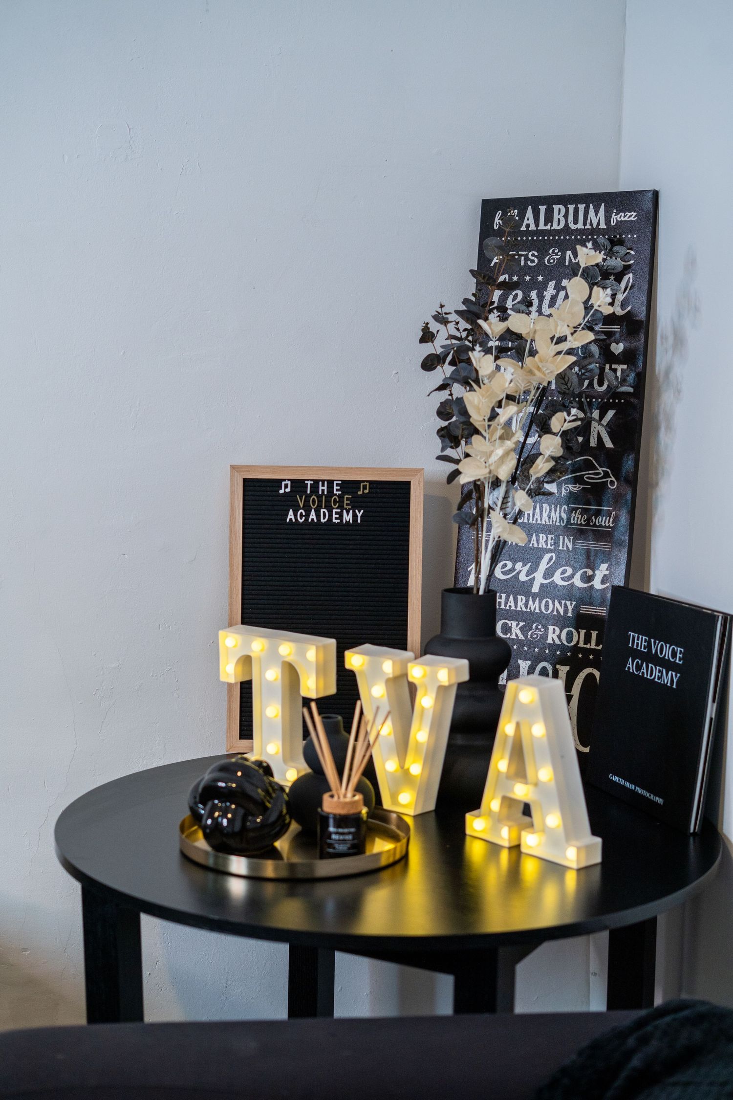 Decorative display with illuminated WA letters and black letter boards on round table.