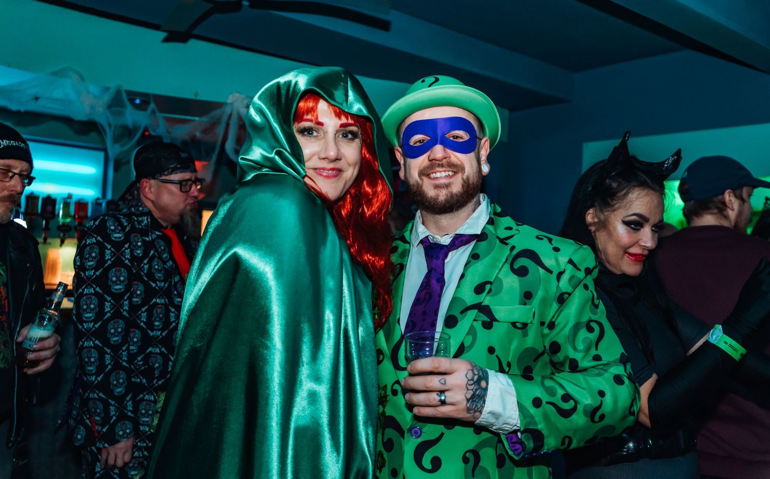 Nightclub crowd in festive green outfits enjoying drinks and music.