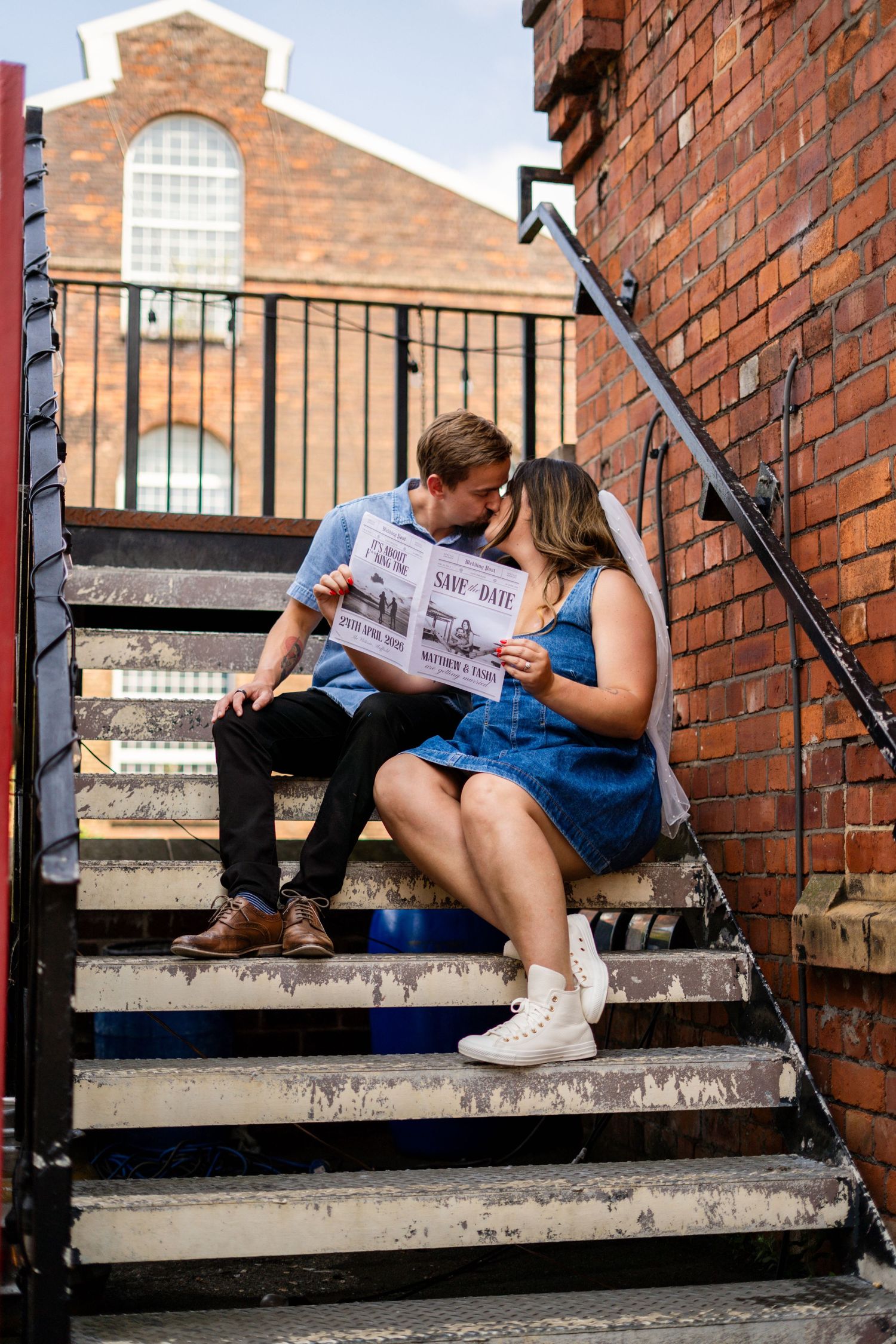 Couple looking at paper while sitting on outdoor steps of brick building.