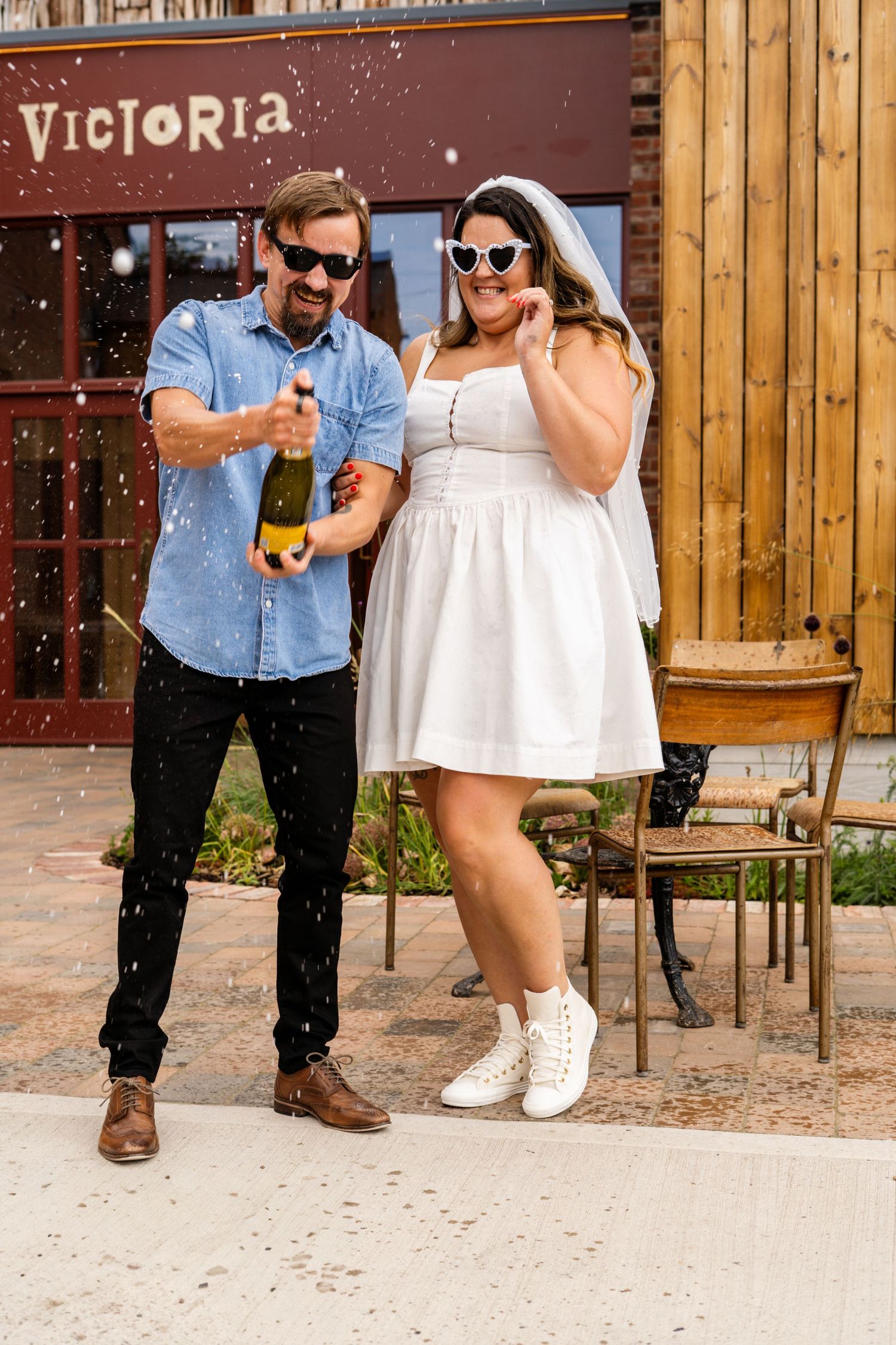 Celebratory moment with champagne outside Victoria venue featuring wooden paneling and brick walls.