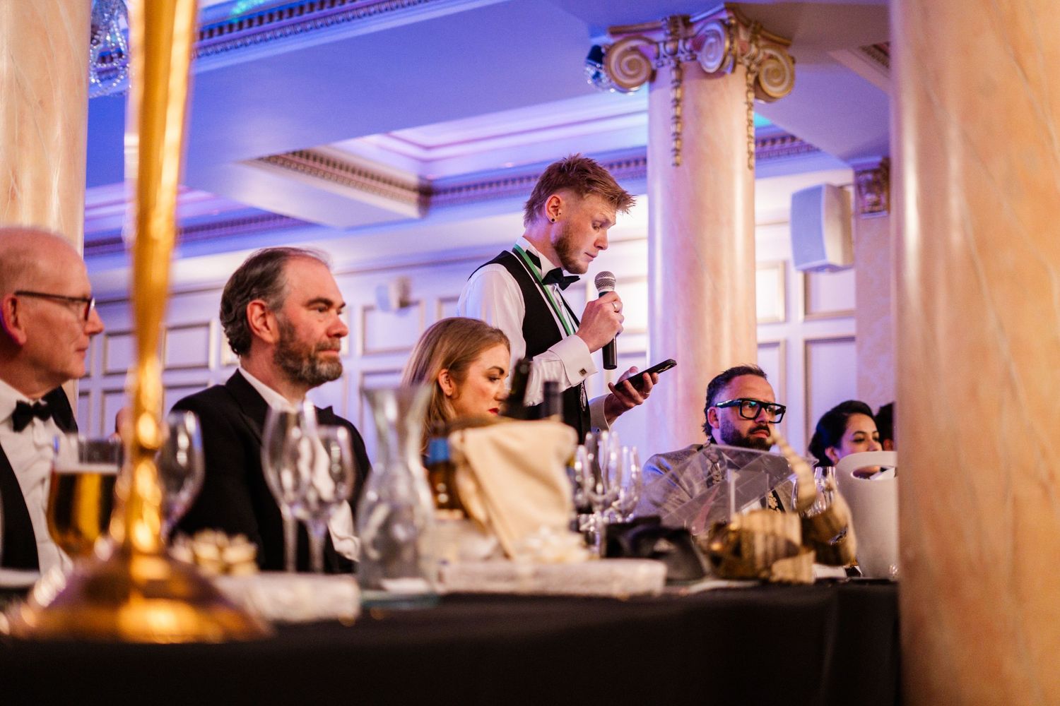 Wedding reception speech captured during elegant indoor celebration with ambient lighting.