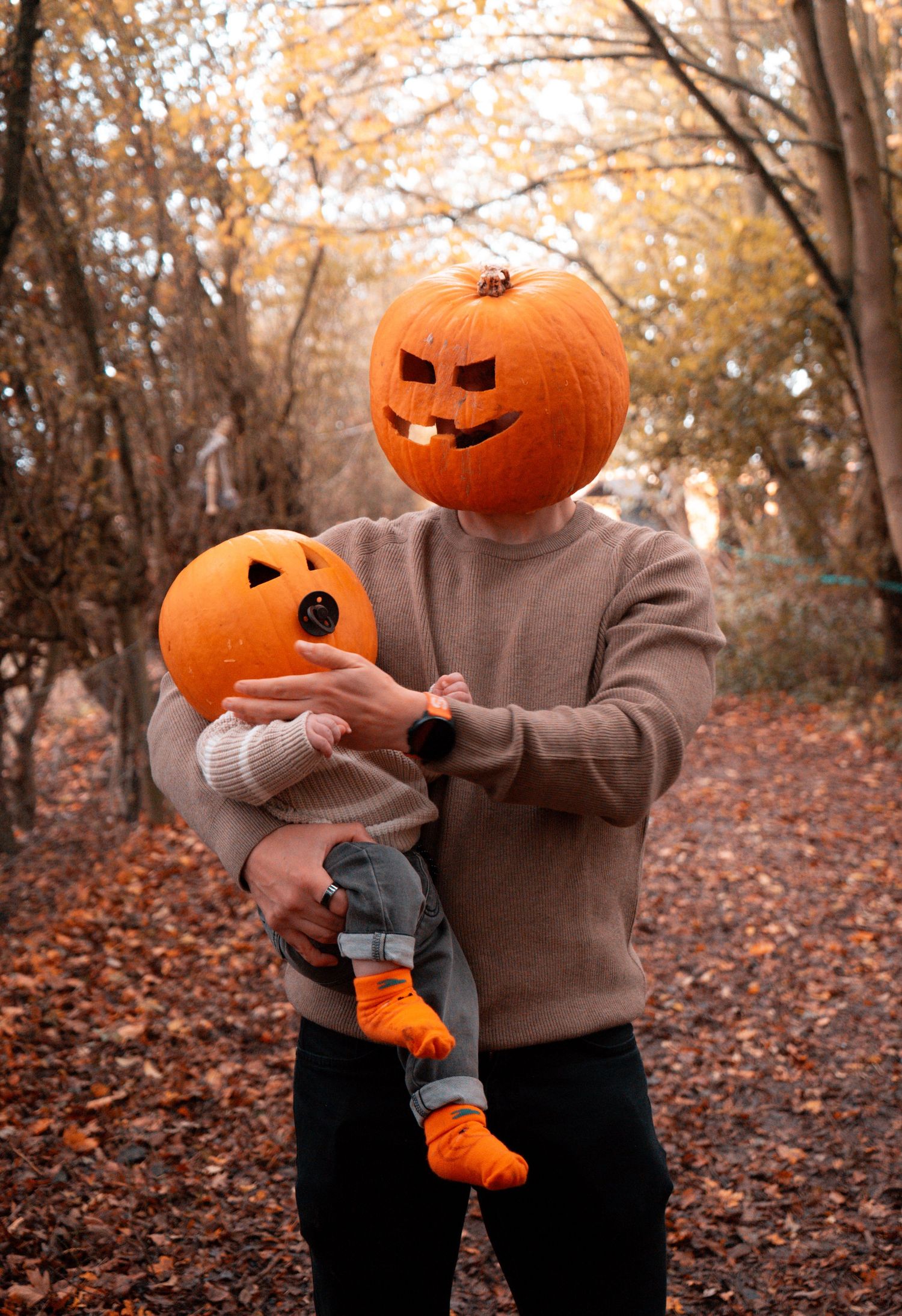 Jack-o'-lanterns with spooky faces in a wooded autumn setting.