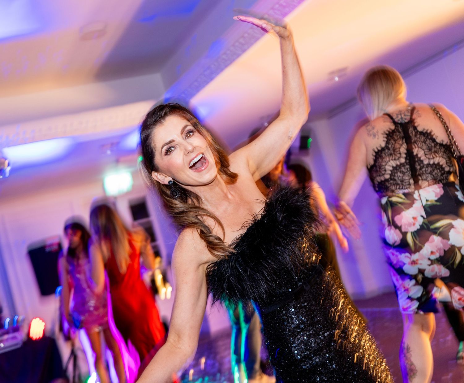 Dance party with dramatic lighting and sparkling dresses on a crowded dance floor.