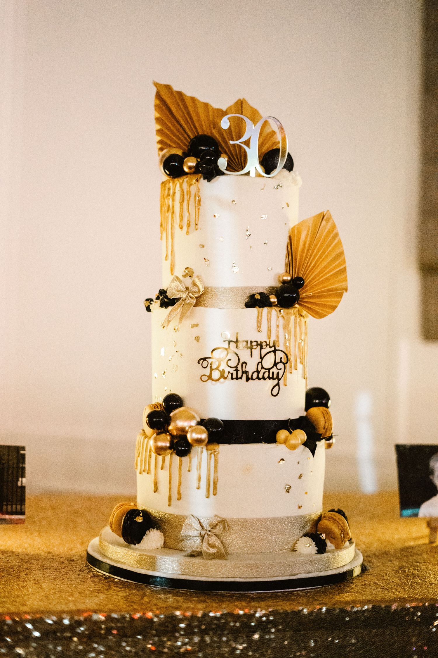 Elegant white wedding cake decorated with gold fans and black floral accents.