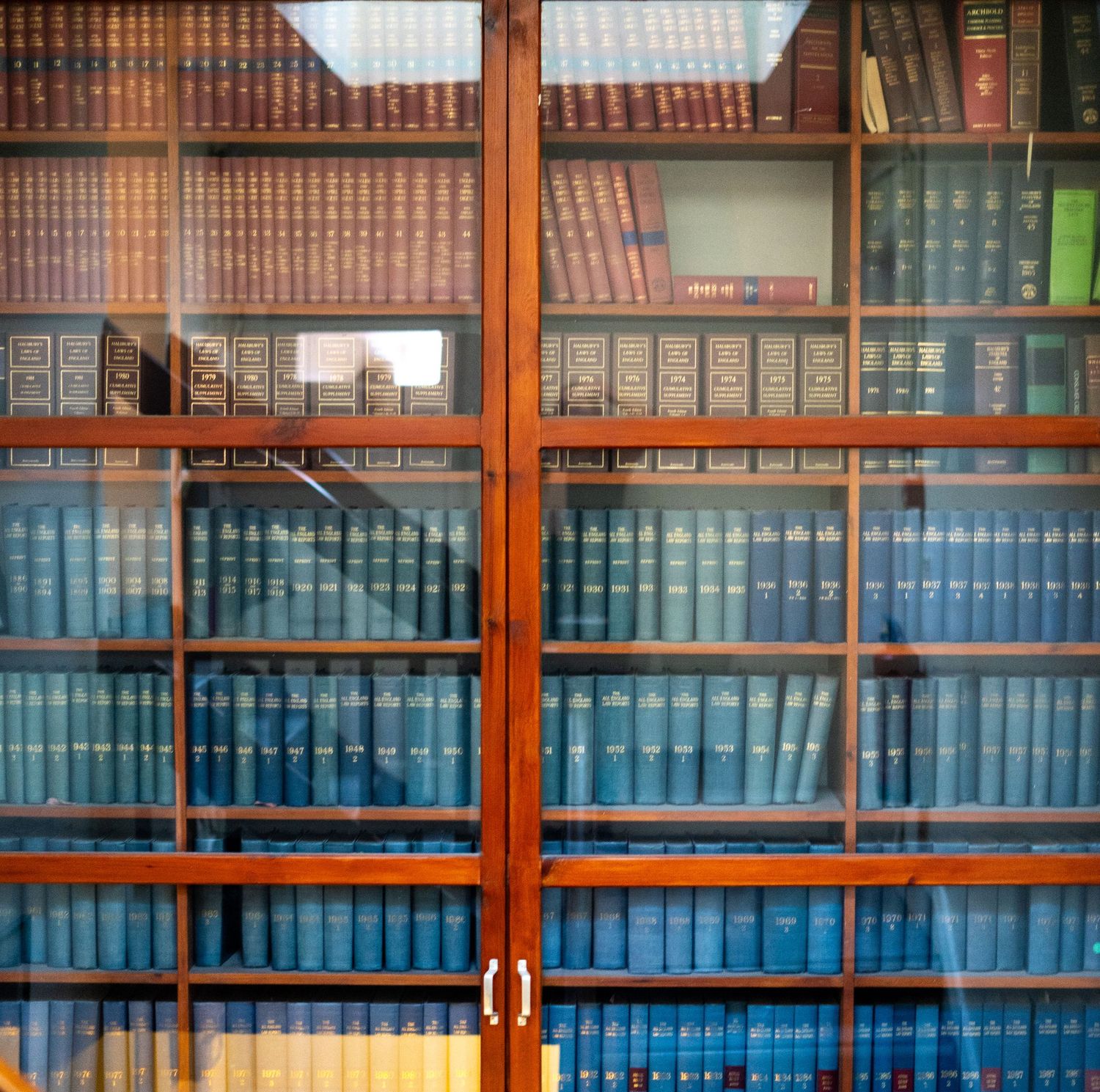 Library shelves filled with rows of matching blue bound books and wooden trim.