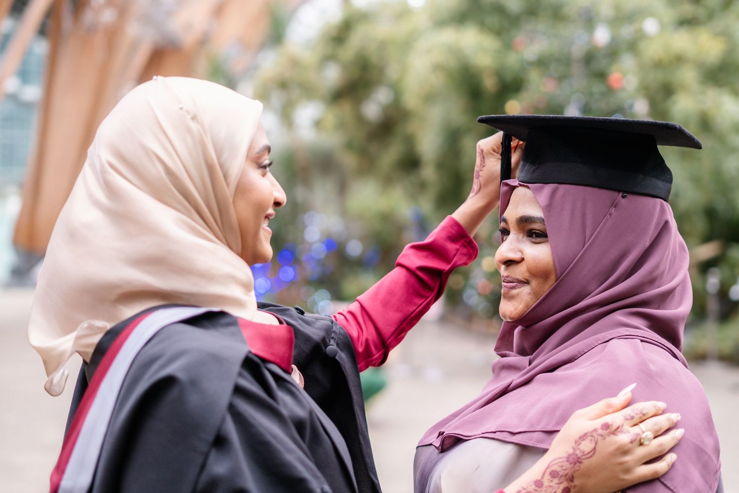 Graduates in academic regalia share joyful moments together outdoors.