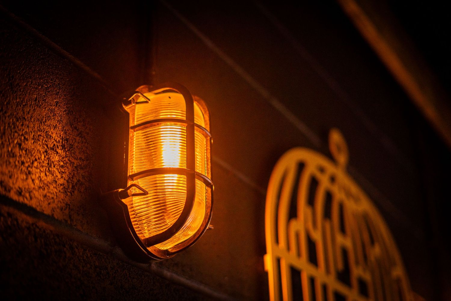 Close-up of vintage-style industrial light fixtures glowing warmly against textured walls.