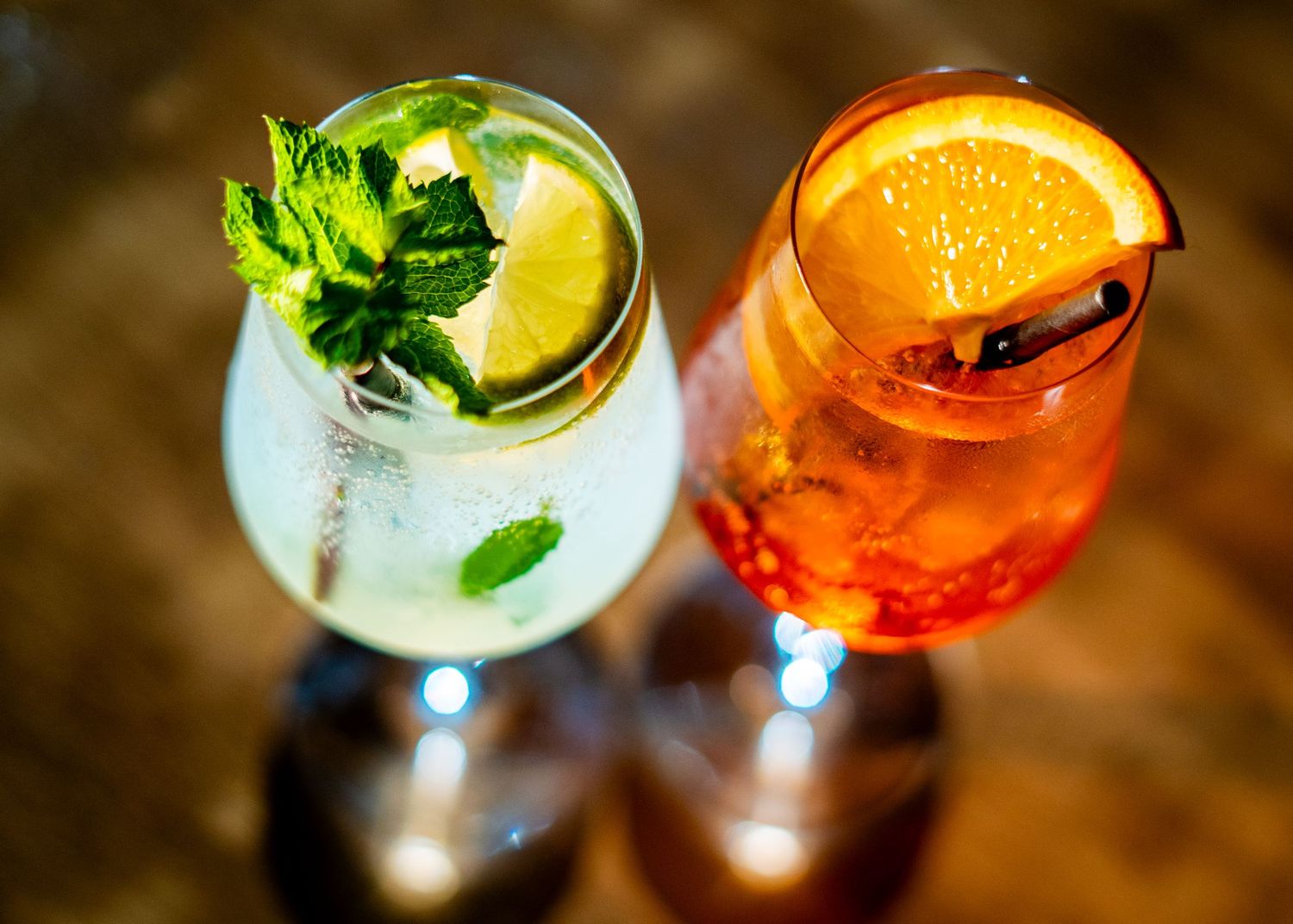 Assorted colorful cocktails with citrus and herb garnishes viewed from above.