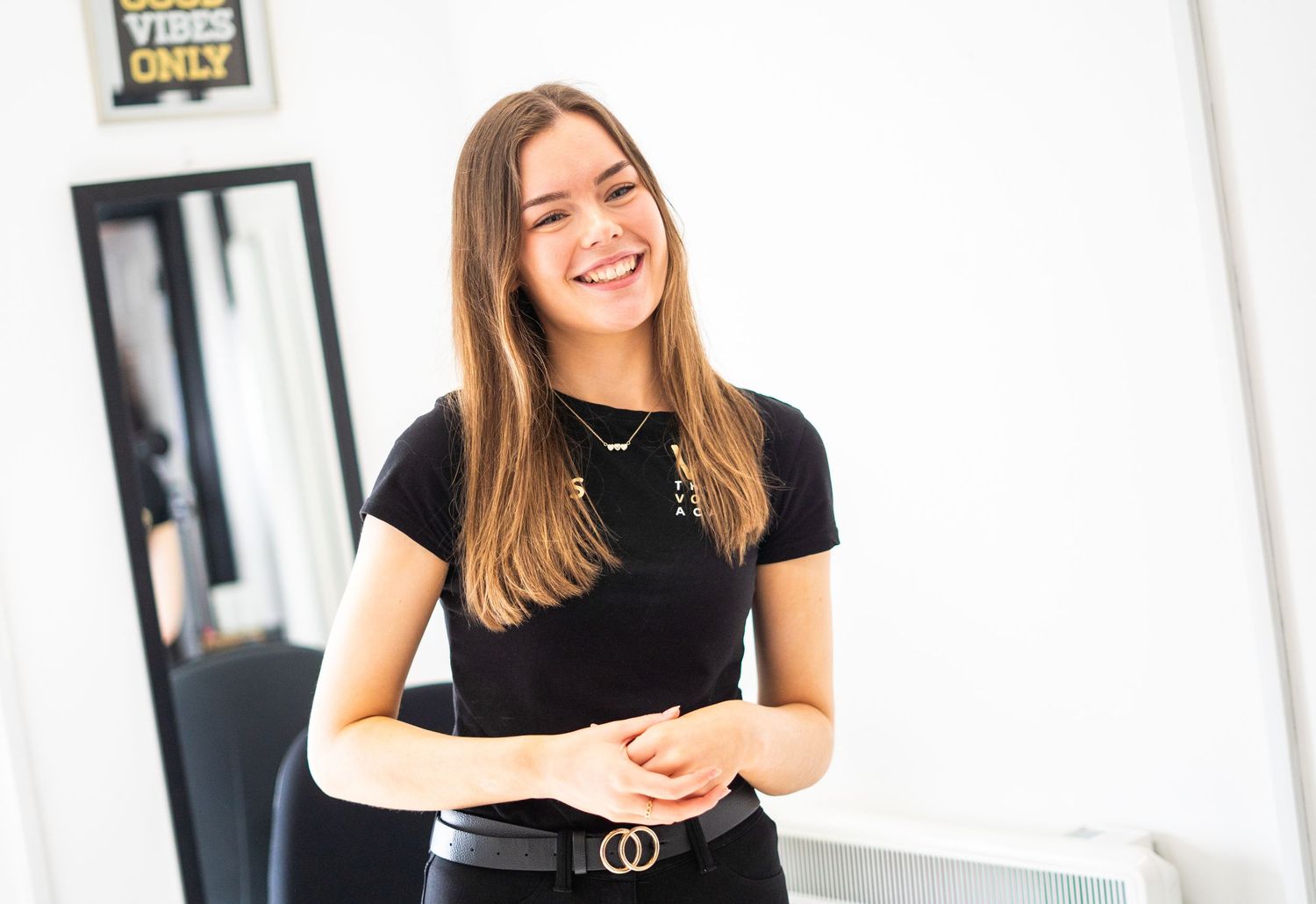 Performer in black t-shirt and belt smiling during vocal training session.