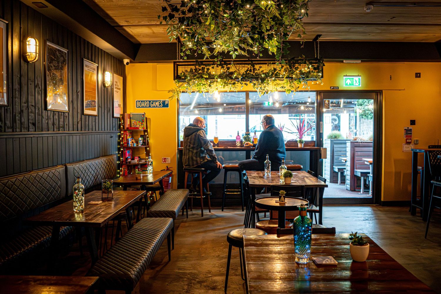 Long view of restaurant dining room with yellow walls and dark wood accents.