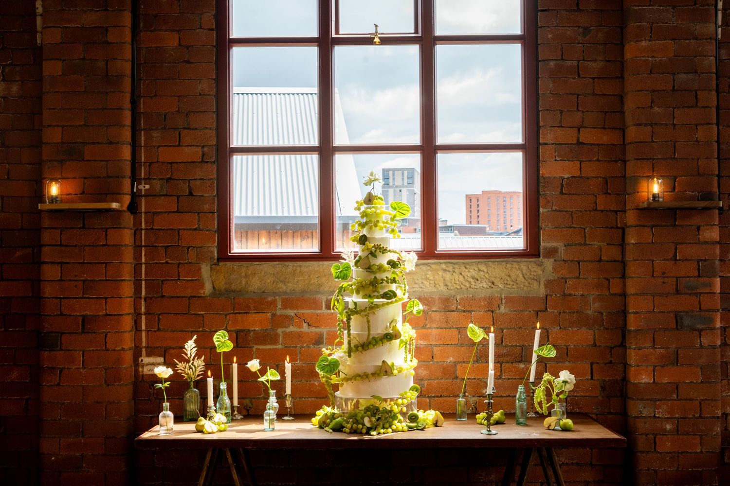 Plants and decor items line windowsills in an industrial brick interior space.