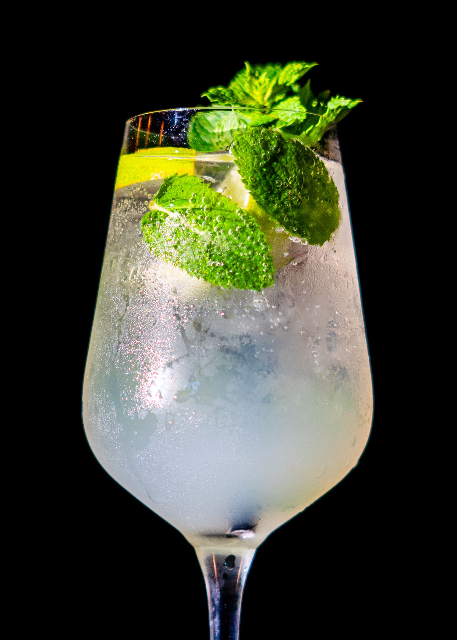 Mint-garnished cocktail in a frosted glass with crushed ice on dark background.