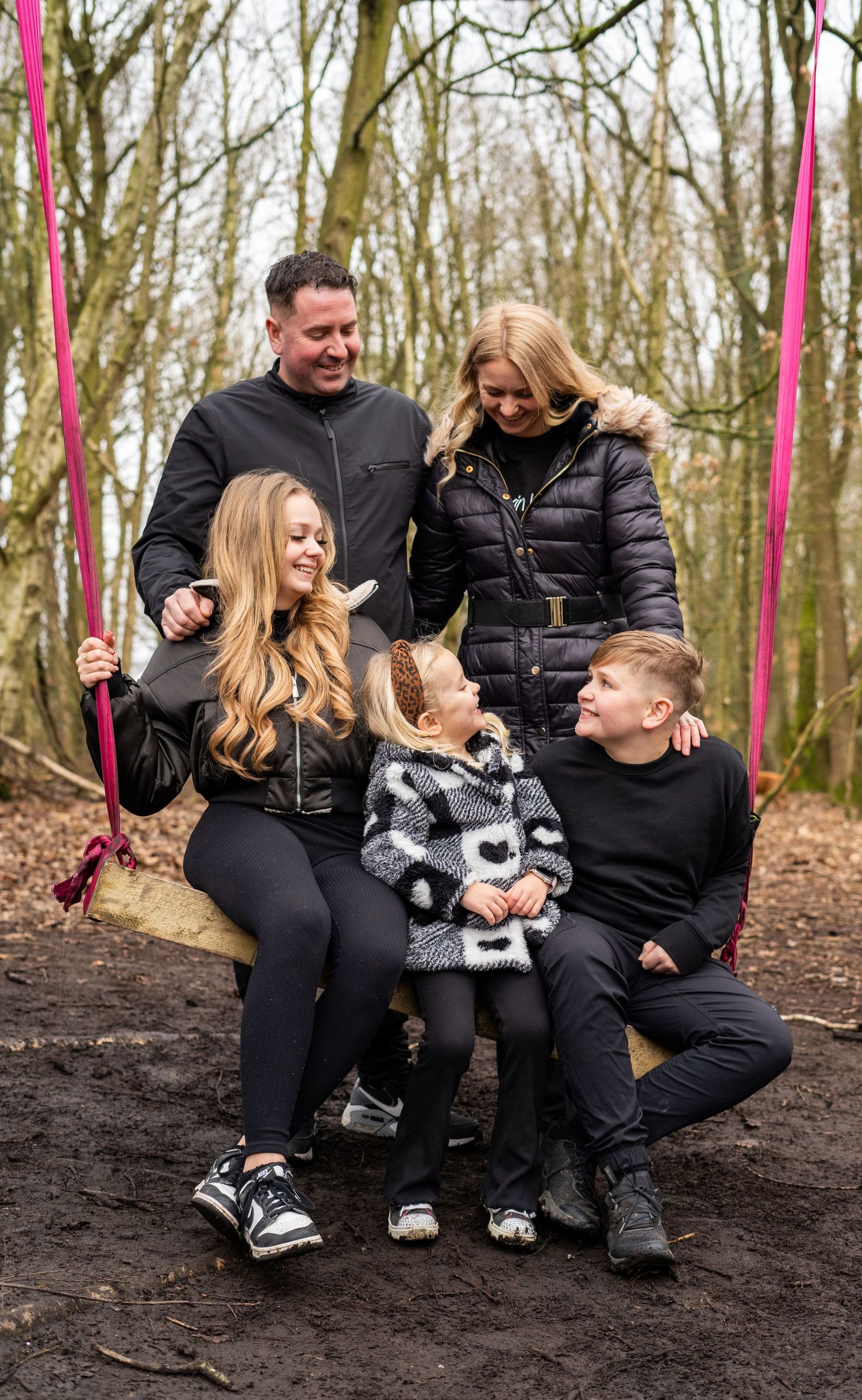 Candid family moment captured during an outdoor photo session in winter woods.
