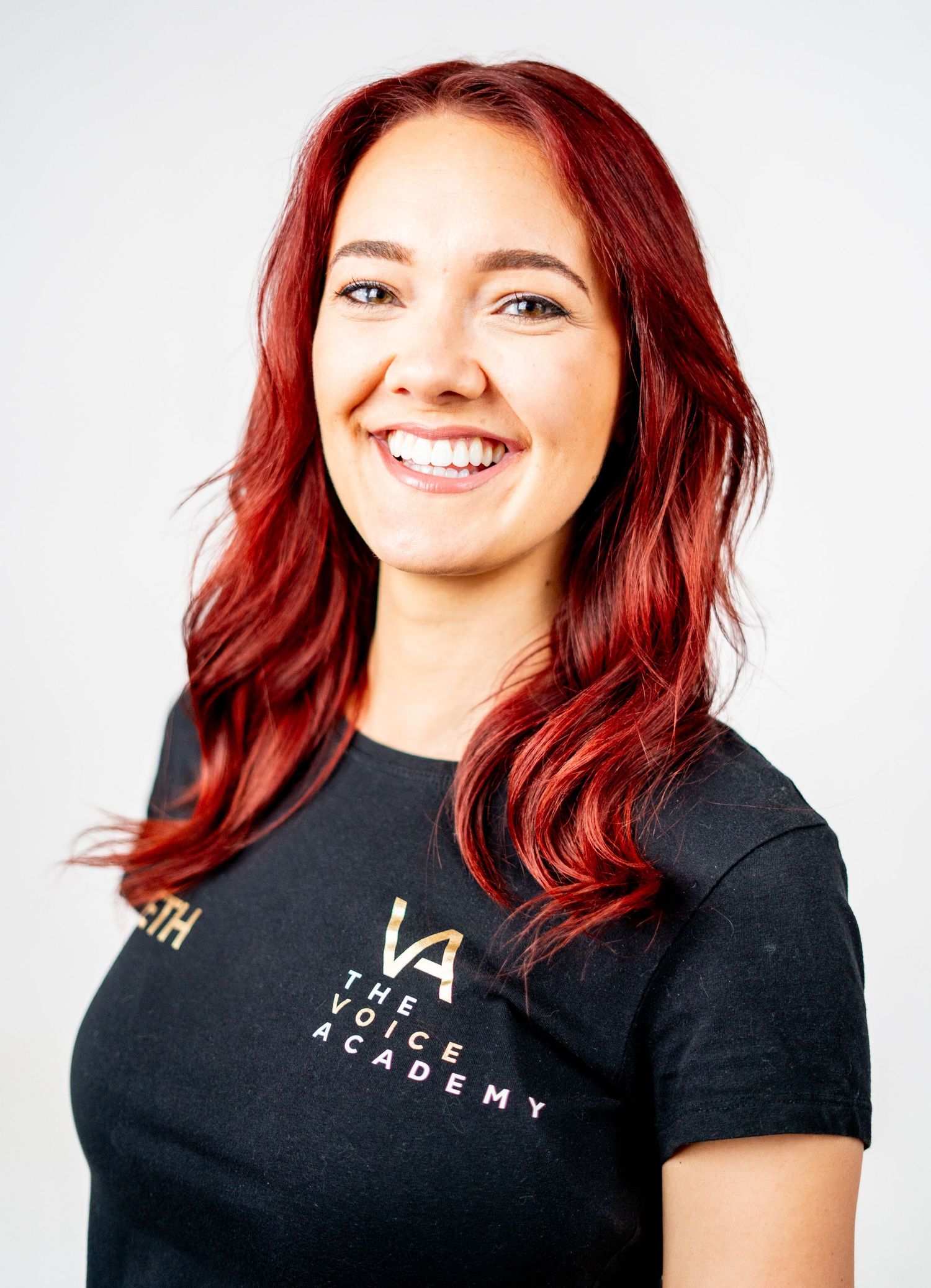 Professional headshots with vibrant red hair wearing black branded t-shirt.