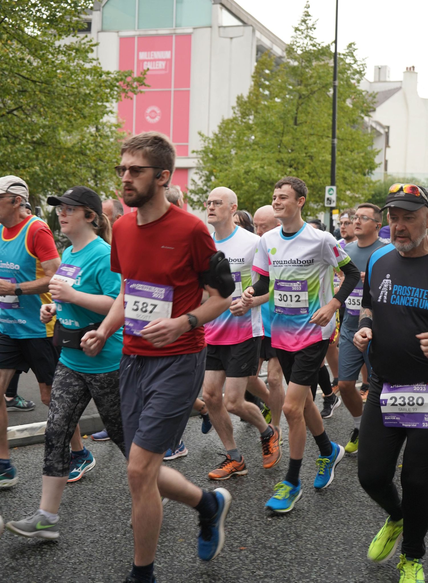 Runners participating in a road race wearing colorful athletic gear on an urban street course.