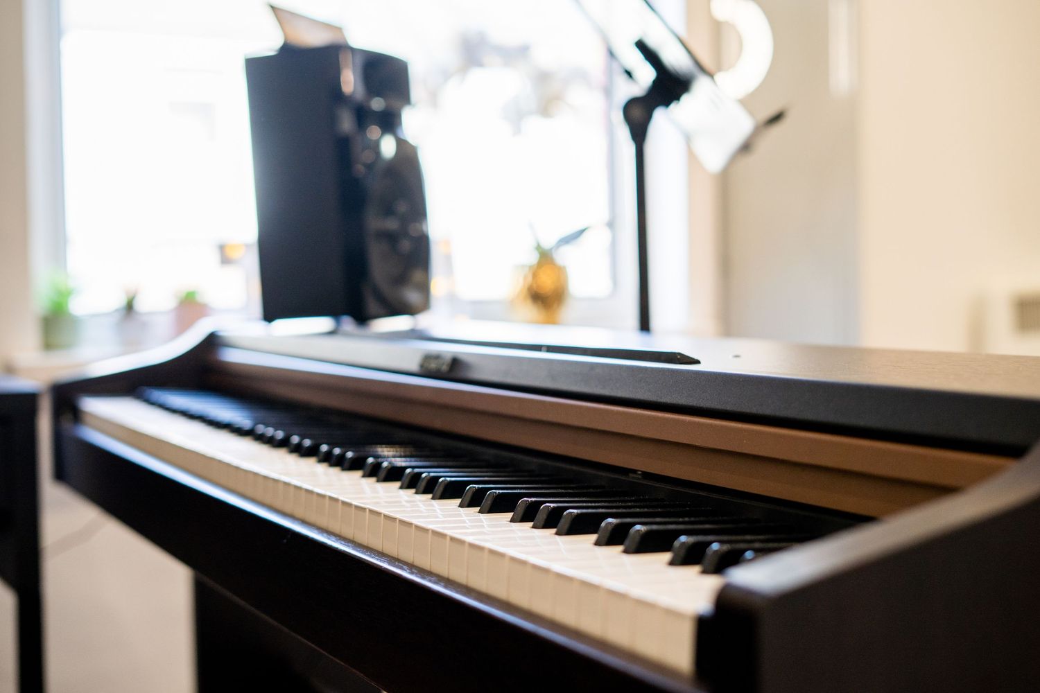 Digital piano keyboard setup in well-lit room with natural lighting.