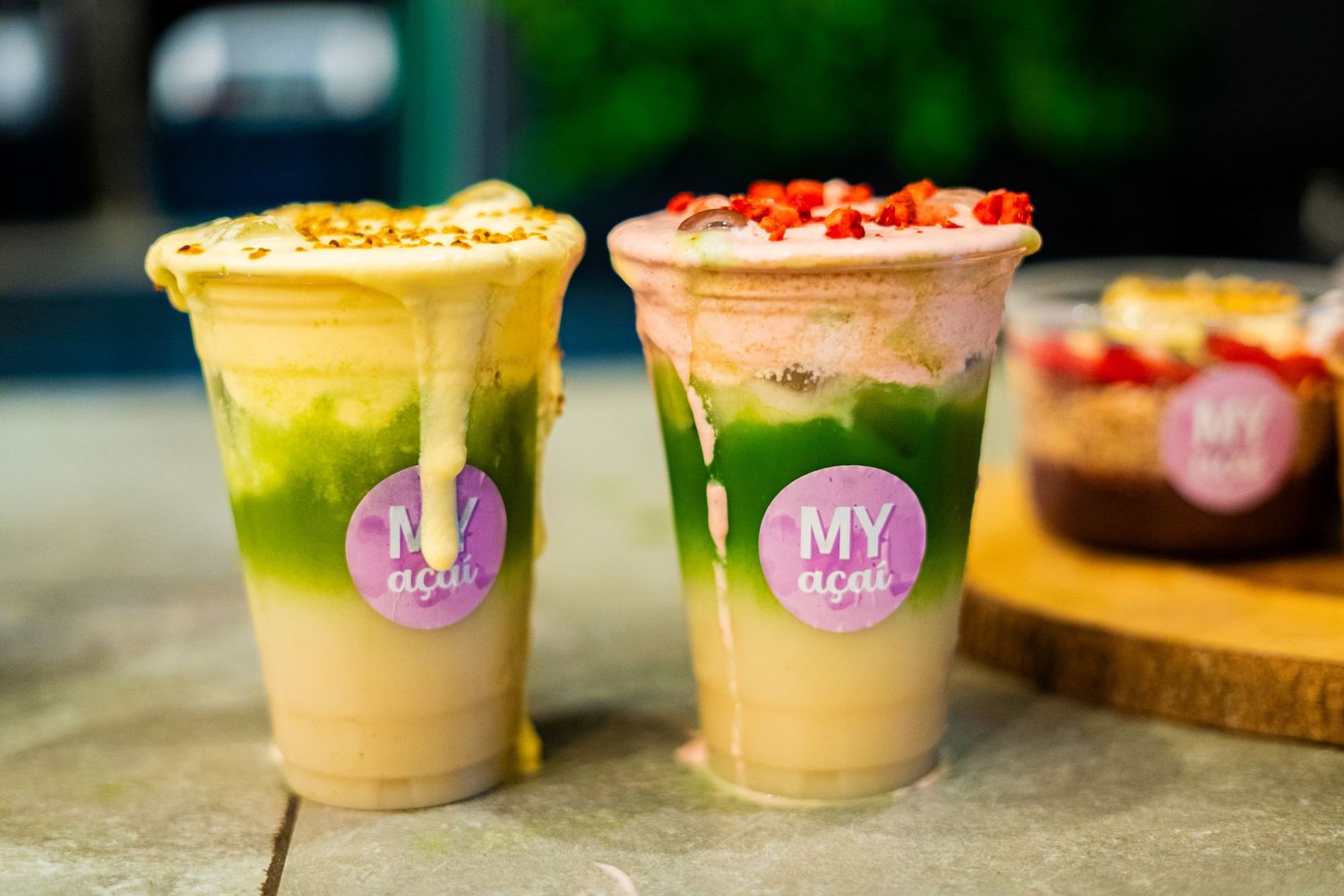 Row of colorful smoothie bowls and drinks displayed on a counter.