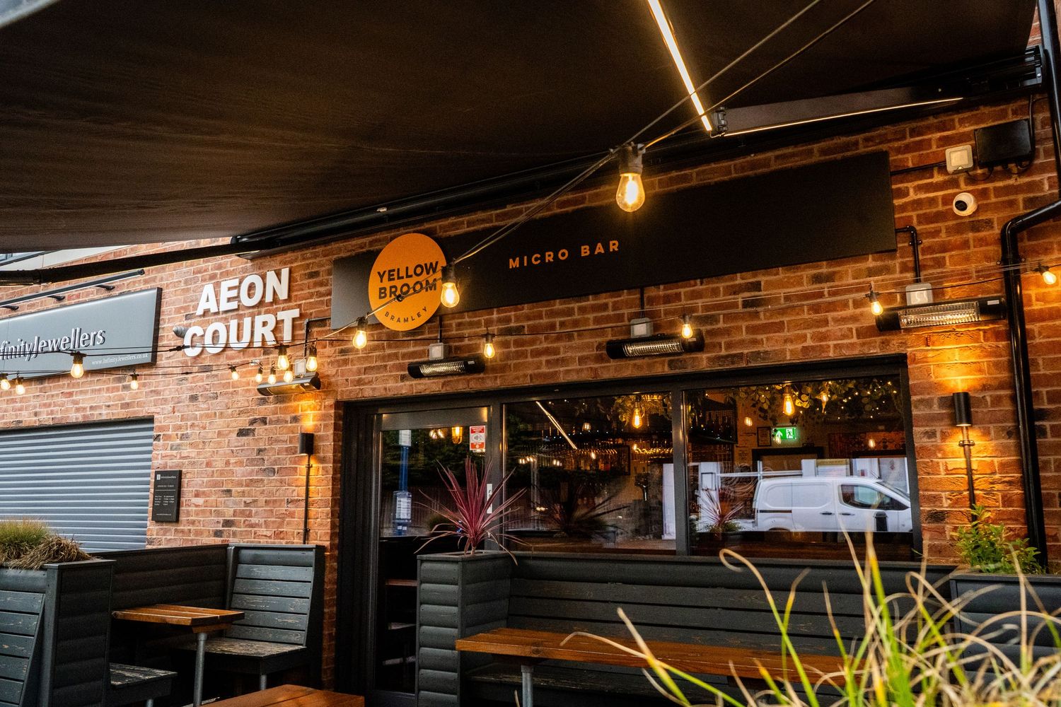 Modern restaurant exterior with outdoor seating area and illuminated signage.
