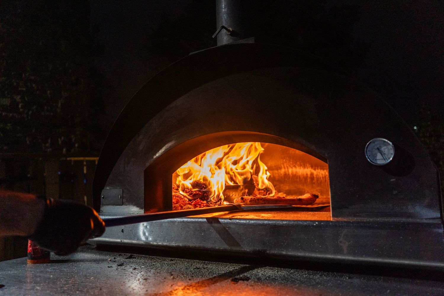Glowing flames inside a traditional brick pizza oven.