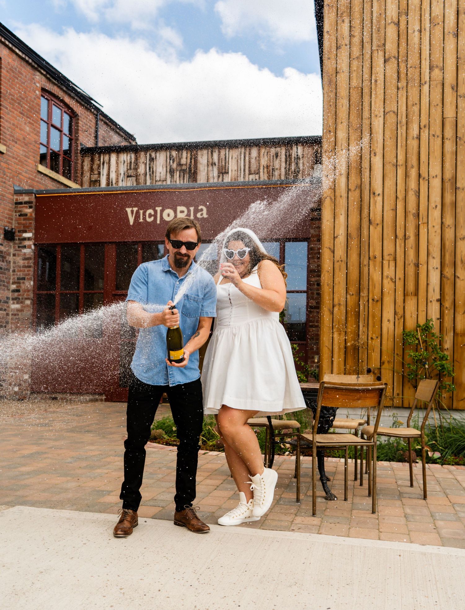 Champagne celebration sequence outside Victoria venue with wooden panels and brick walls.