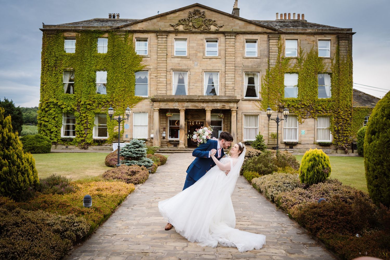 Romantic wedding portraits at a historic ivy-covered mansion with manicured gardens.