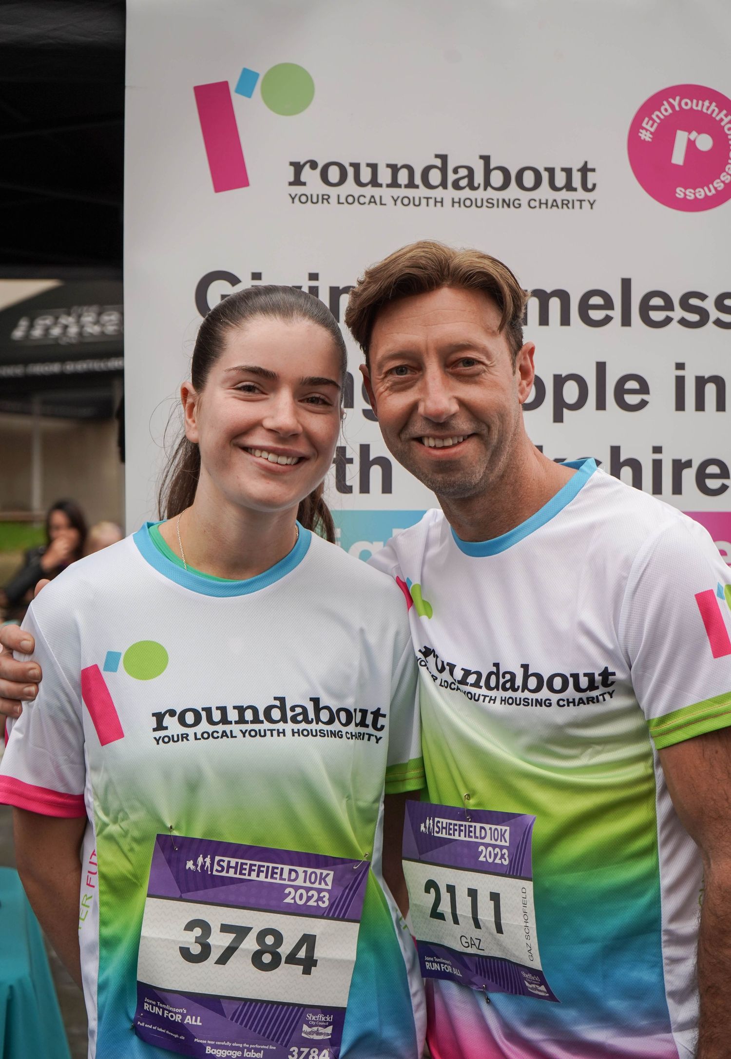 Participants in matching gradient shirts display their race numbers at a charity running event.