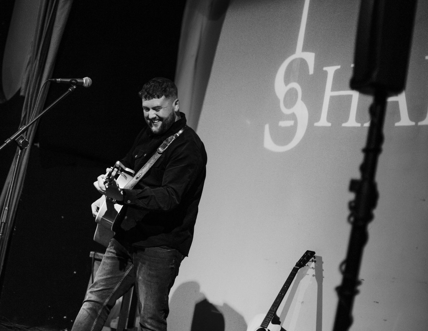 Stage performance with white text projection and dramatic side lighting.