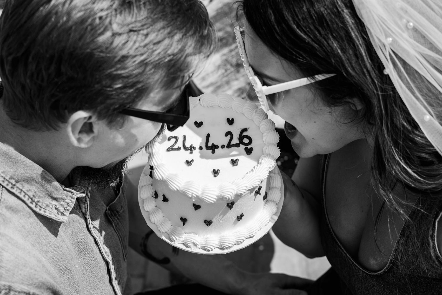 A black and white artistic photo of a couple with a cake.