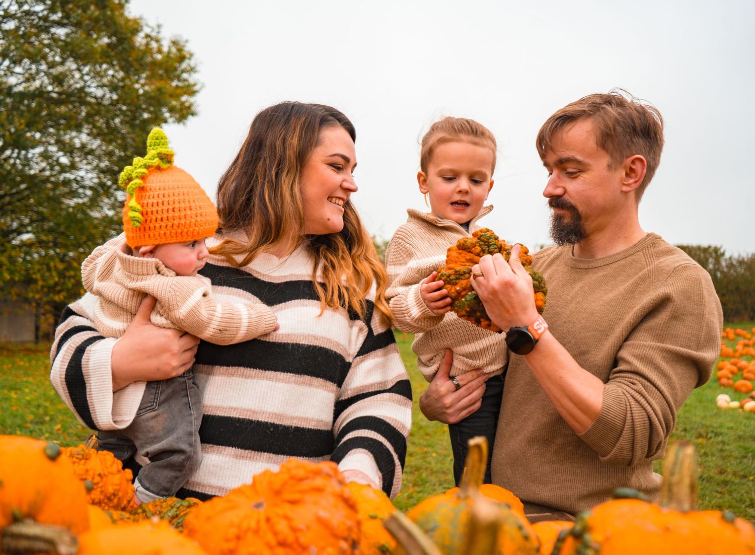 Family examines pumpkins together during fall harvest season.
