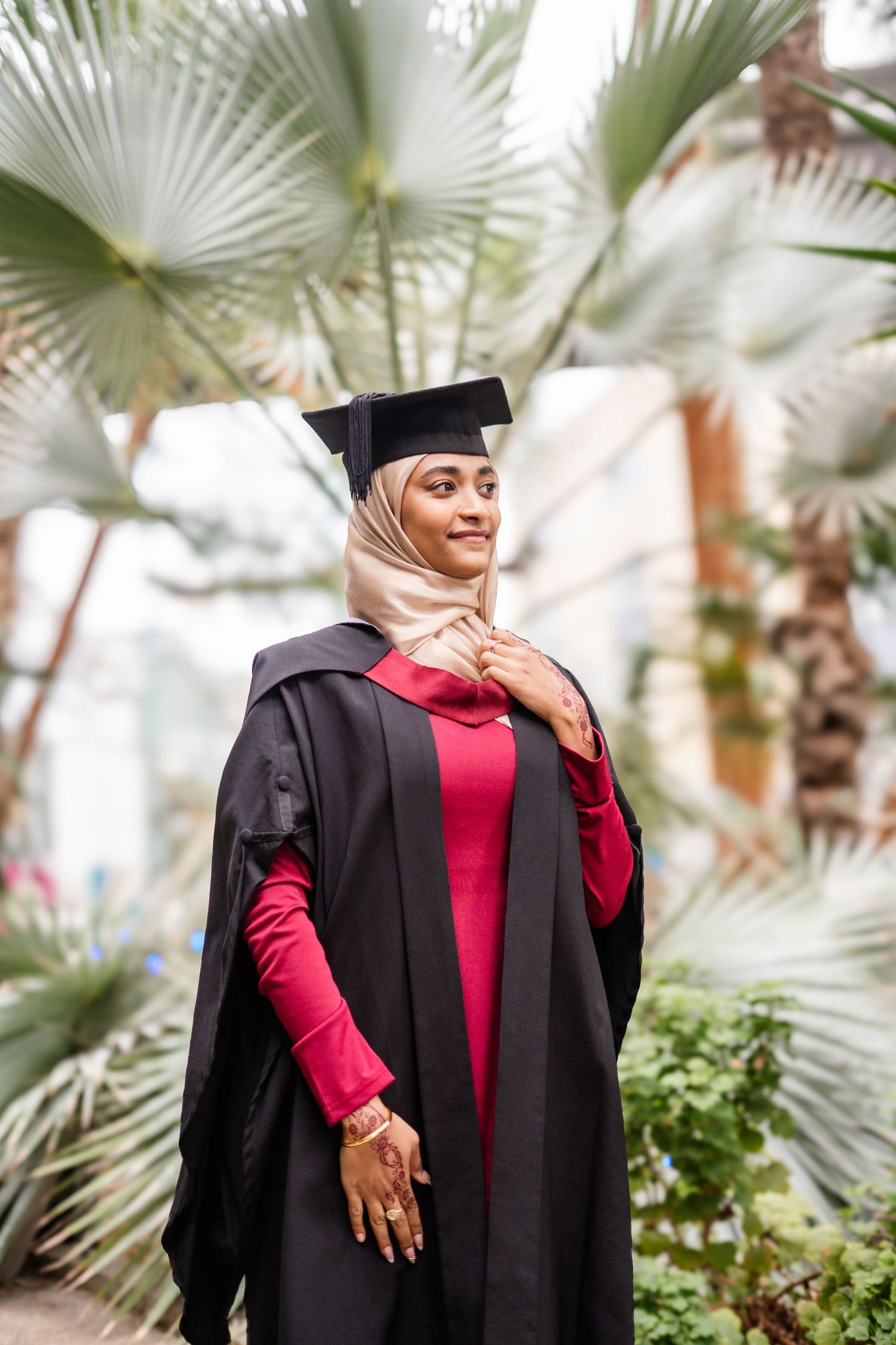 Graduation portrait session in botanical garden with palm fronds in foreground.