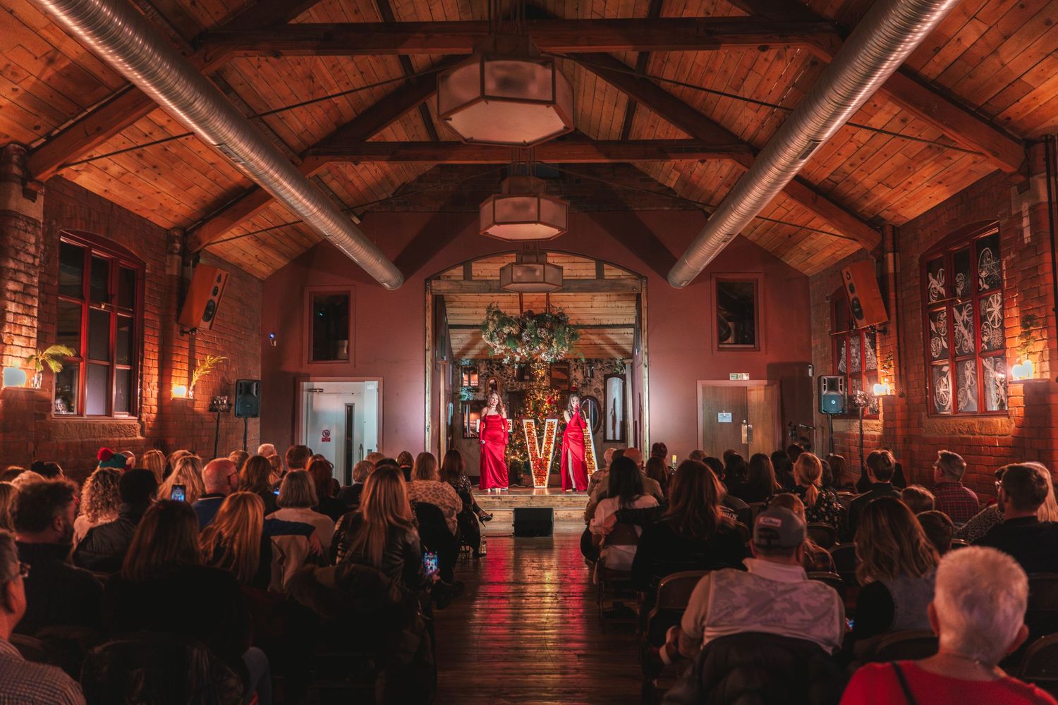 Wedding ceremony in elegant wood-beamed hall with decorative floral arrangements.